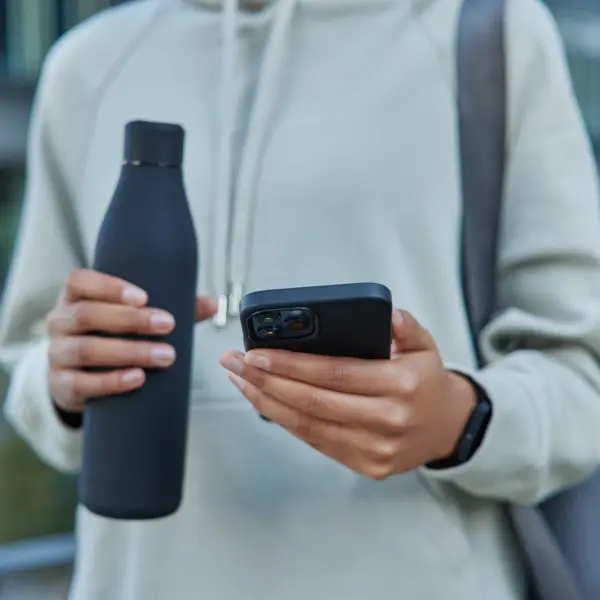 cropped-shot-sportswoman-casual-hoodie-holds-bottle-water-mobile-phone-checks-fitness-activity-carries-rolled-mat-poses-outdoors (1)